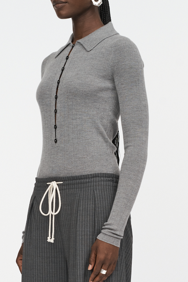 Maria McManus Kissing Placket Polo in Heather Gray. Merino slow wool. Slim fit polo sweater. Placket detain on sweater. Elongated sleeved sweater. Modern Silhouette Sweater. Modern Sophisticated sweater. Maria McManus Heather Grey sweater. Glimpse of skin sweater. Button detail peak of skin. Light grey Polo sweater. Merino Wool Heather Gray sweater. McManus kissing sweater. McManus Heather Gray. Maria McManus beautiful long sleeved Heather Gray Polo Sweater. Light Gray McManus merino sweater. 